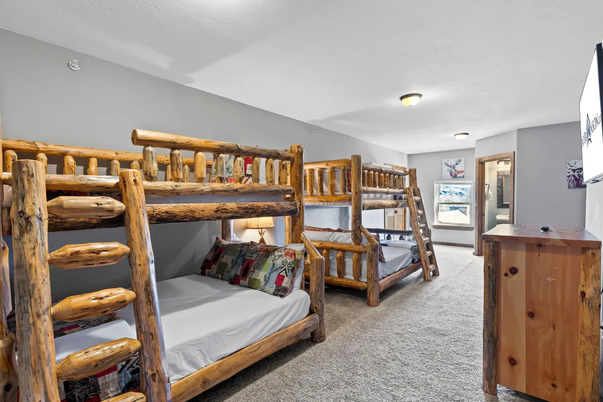 A playful and inviting bunk room with multiple bunk beds, wooden furniture, and colorful decorative pillows. The space is designed for group fun, sleepovers, and nighttime adventures, making it ideal for kids.