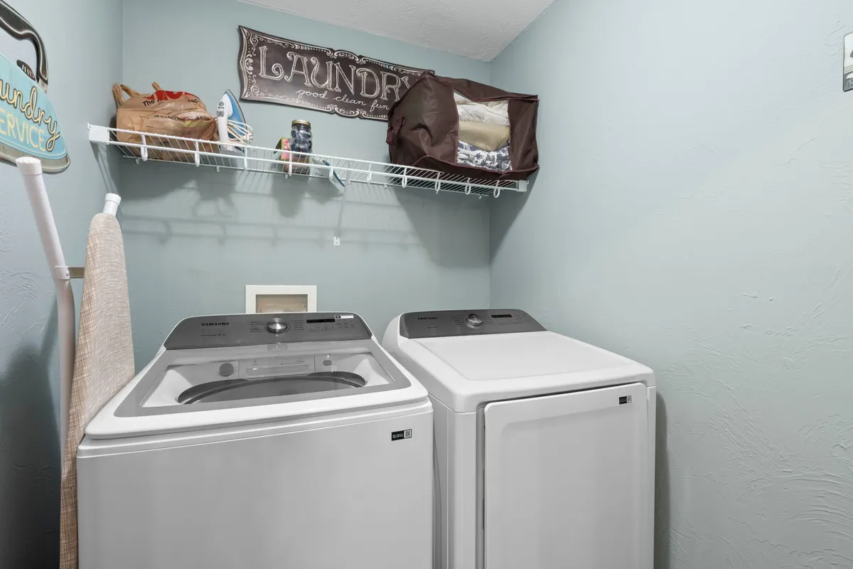 A compact, practical laundry space with a washing machine and dryer, shelving for laundry supplies, and a decorative 'laundry' sign. The area is tidy and functional, ideal for family use or longer stays.